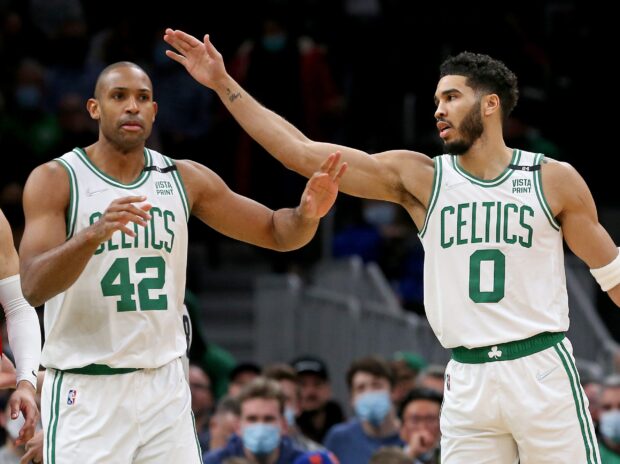 Two Boston Celtics players celebrating during a basketball game in white uniforms