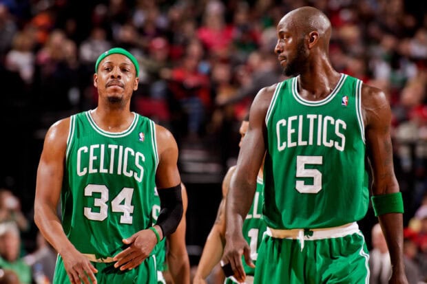 Two Boston Celtics players in green jerseys walking on the basketball court during a game