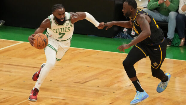 Boston Celtics player dribbling the basketball during a game against a defender