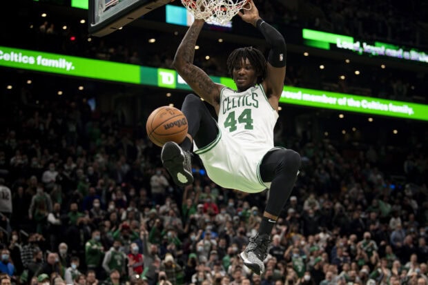 Boston Celtics player dunking the basketball during a game in front of a crowd