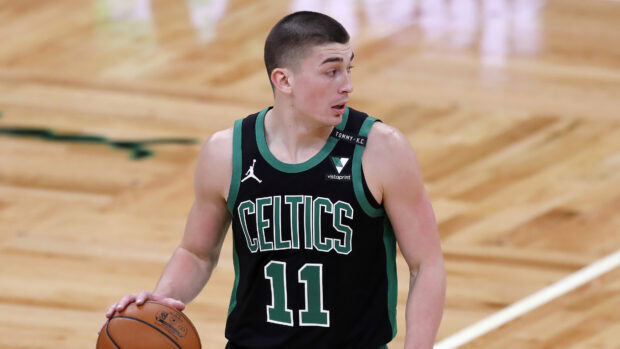Boston Celtics player wearing black jersey holding basketball on court