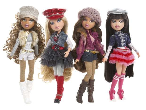Four stylish Bratz dolls wearing fashionable outfits and hats standing in a row