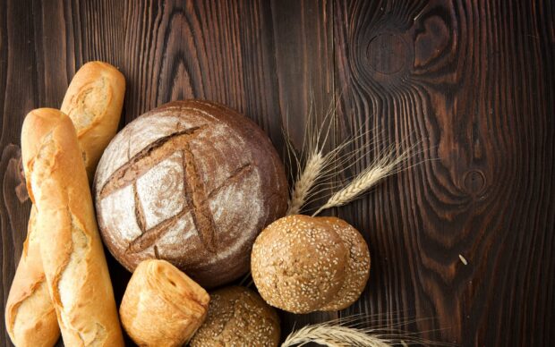 Fresh bread assortment with wheat ears on rustic wooden surface