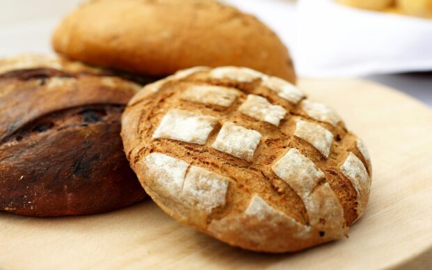 Freshly baked bread with crusty texture and flour dusting on wooden surface