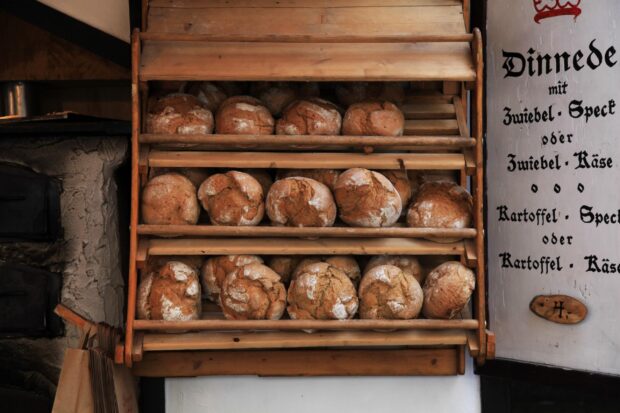 Freshly baked rustic bread stacked on wooden shelves inside a bakery