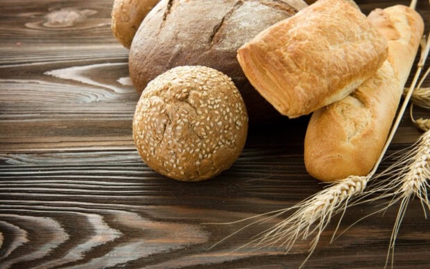 Fresh bread assortment with sesame seeds and wheat on wooden table