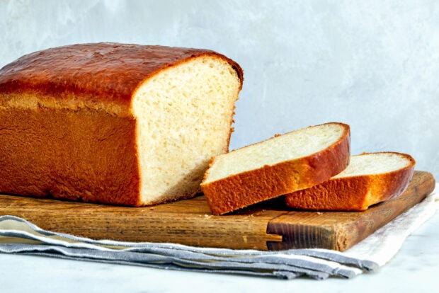 Fresh bread loaf with two sliced pieces on a wooden cutting board