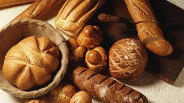 Freshly baked bread assortment on a wooden board and cloth basket
