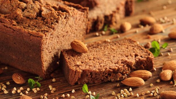 Homemade bread with almonds and fresh herbs on wooden table