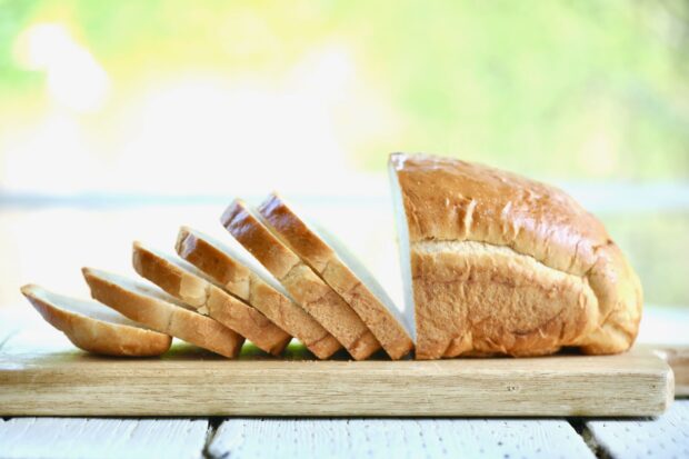 Sliced bread arranged neatly on a wooden cutting board with a blurred green background