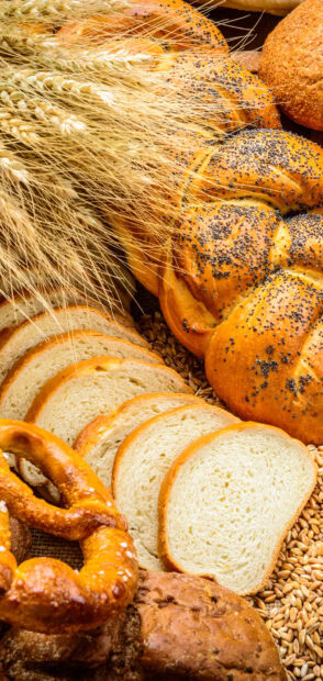 Fresh bread loaves and wheat stalks arranged on a rustic surface
