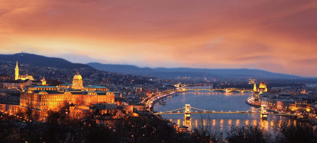 Historic Budapest cityscape with the river and illuminated bridges at sunset