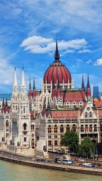 The Hungarian Parliament building in Budapest with a clear blue sky and the Danube river in the foreground