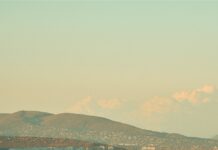 The historic Parliament building in Budapest is viewed from above with autumn trees and the Danube River