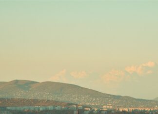 The historic Parliament building in Budapest is viewed from above with autumn trees and the Danube River