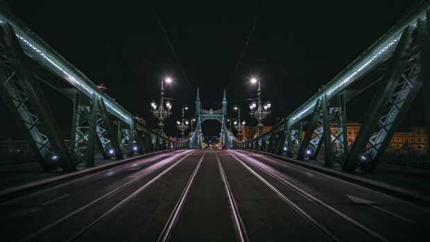 Night view of Budapest bridge with street lamps and tram tracks in clear detail