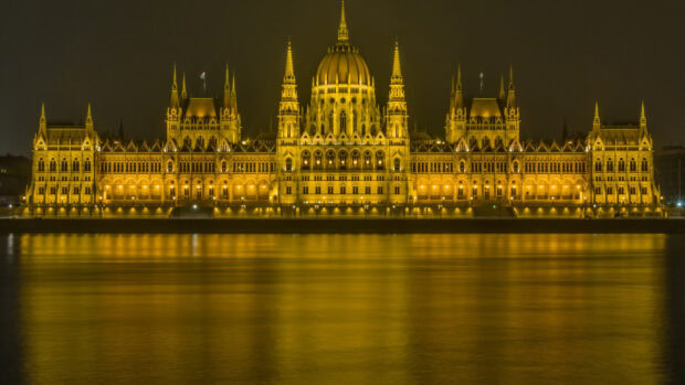 The Parliament building in Budapest illuminated at night with golden lights reflecting on the river