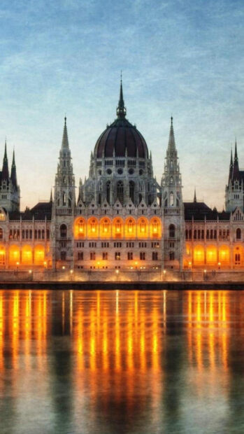 The Budapest architecture reflecting on water at dusk with glowing lights