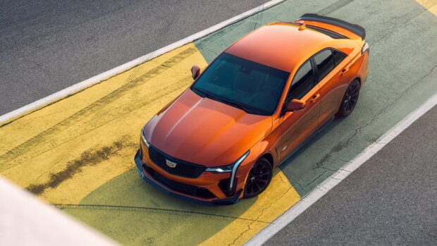 Orange Cadillac parked on a yellow marked road section viewed from above