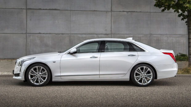 Silver Cadillac parked beside a concrete wall in a high resolution profile view