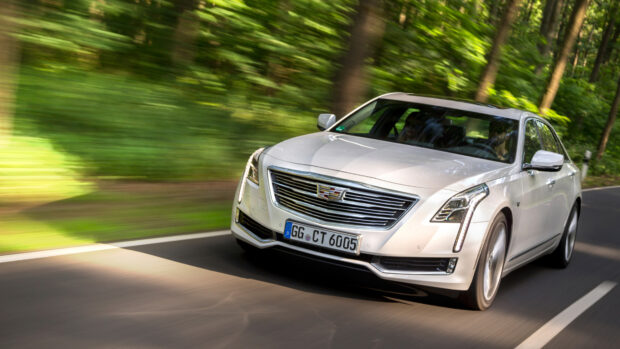 White Cadillac driving fast on a forest road with motion blur around the car