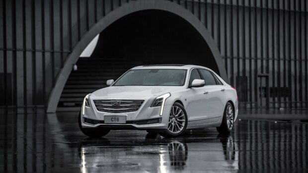 White Cadillac parked in front of a modern architectural structure with wet reflective floor