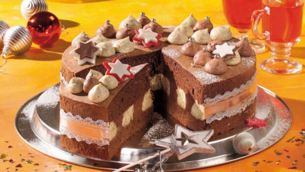 Chocolate cake decorated with creamy frosting and star shaped decorations on a silver tray