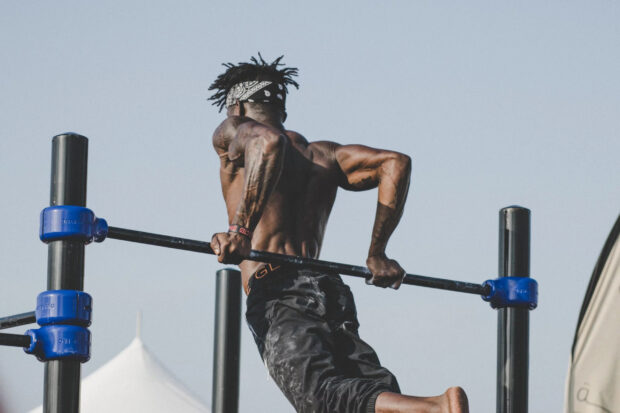 Muscular man performing calisthenics workout on parallel bars outdoors