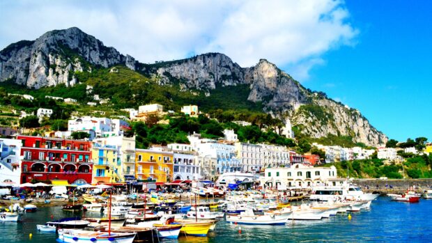 Colorful houses and boats in Capri Island harbor under clear blue sky