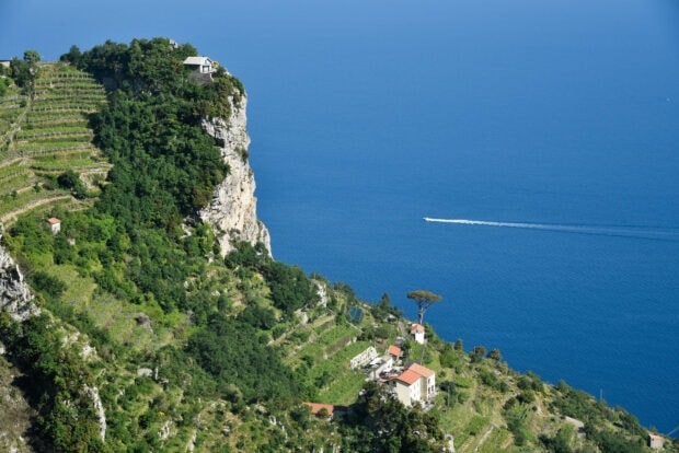 A scenic view of Capri Island with green cliffs and a boat on the blue sea