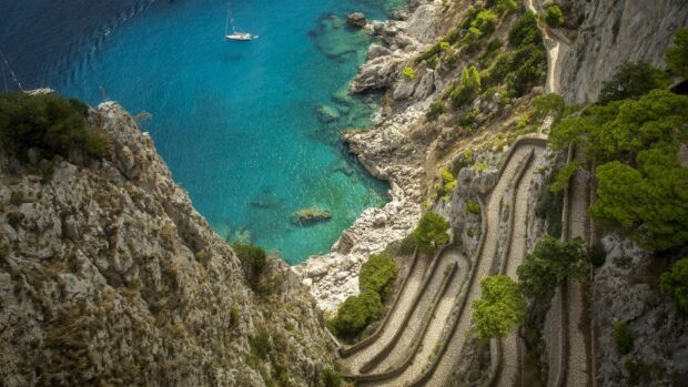 Scenic winding path along Capri Island coastline with clear turquoise water