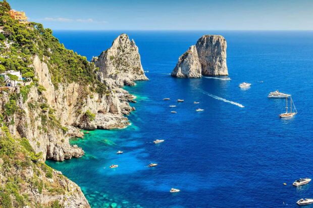 Stunning Capri Island coastline with rocky cliffs and boats on clear blue sea