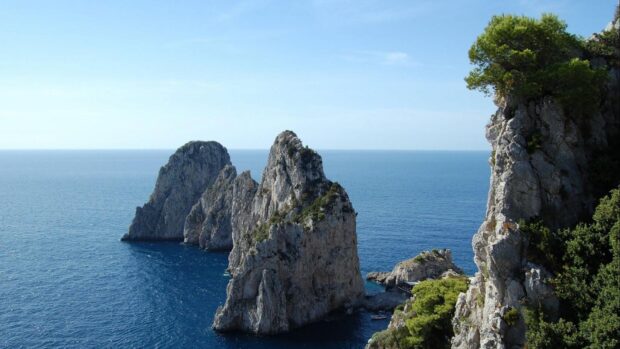 Stunning Capri Island rocky cliffs surrounded by deep blue sea and clear sky