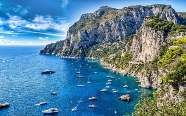 Stunning Capri Island view with clear blue sea and boats along the rocky coastline