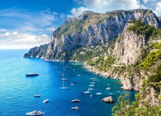 Stunning view of Capri Island with boats sailing along the blue sea near rocky cliffs