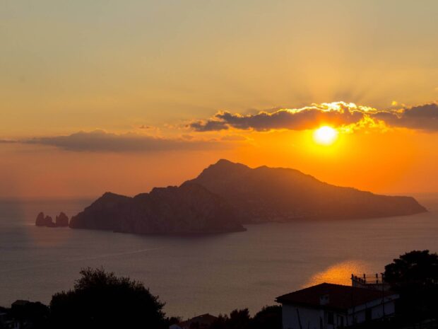 Sunset view of Capri Island with vibrant orange sky and calm sea