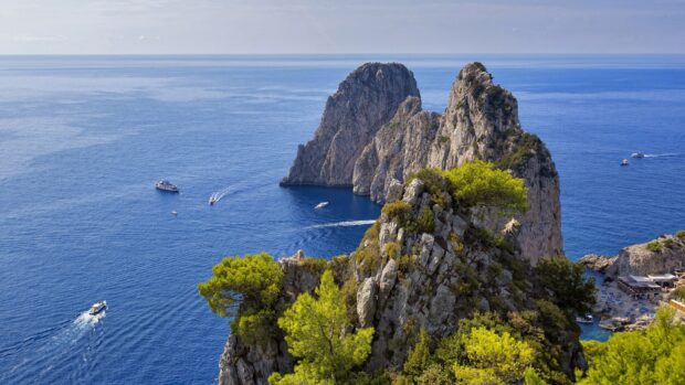 The scenic Capri Island with rocky cliffs and boats cruising in the blue sea