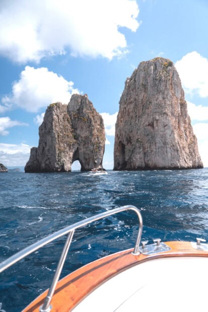 View of Capri Island rocks from a boat on the blue sea under a bright sky