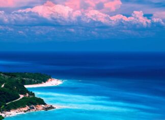 Tropical Caribbean Islands coast with clear blue water and lush green trees under pink clouds