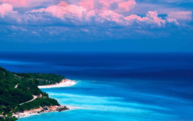 Tropical Caribbean Islands coast with clear blue water and lush green trees under pink clouds