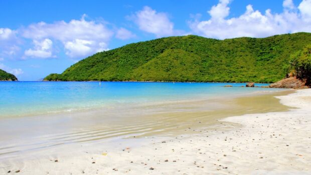 Clear blue sea and green hills in the Caribbean Islands with smooth sandy beach