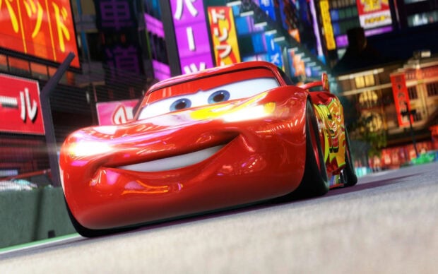 Lightning McQueen racing through a colorful city street with bright lights and signs