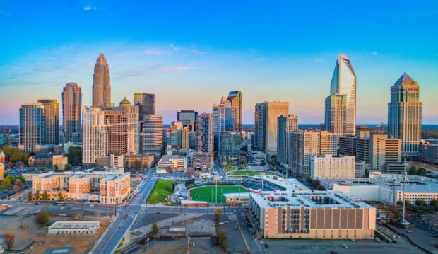 Charlotte skyline featuring modern skyscrapers and a baseball stadium under a clear blue sky