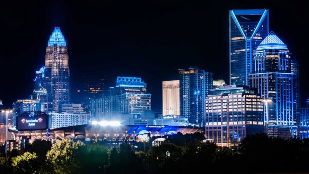 The Charlotte skyline at night with illuminated buildings and stadium in clear view