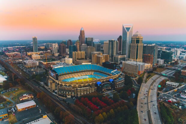 A panoramic view of Charlotte skyline at sunset featuring the stadium and cityscape