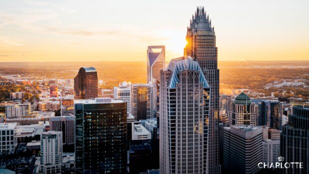 Aerial view of Charlotte skyline with tall buildings and sunset light illuminating the cityscape