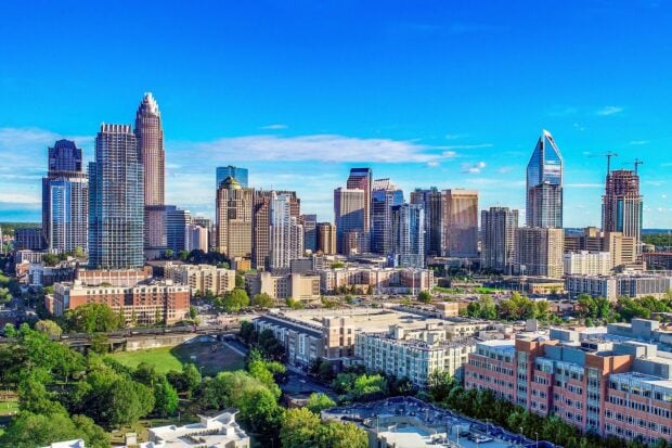 A high definition shot of Charlotte skyline featuring tall buildings and urban greenery under a clear sky