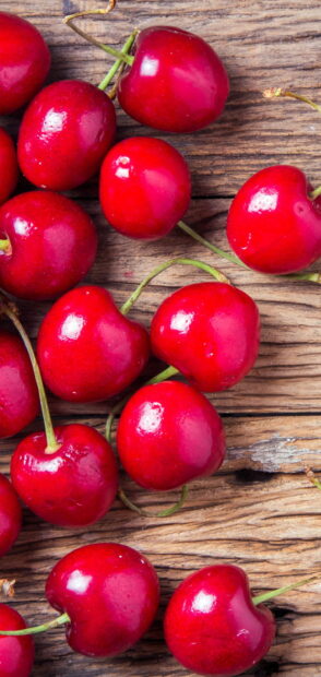 Fresh ripe cherry fruits scattered on rustic wooden surface with vibrant red color