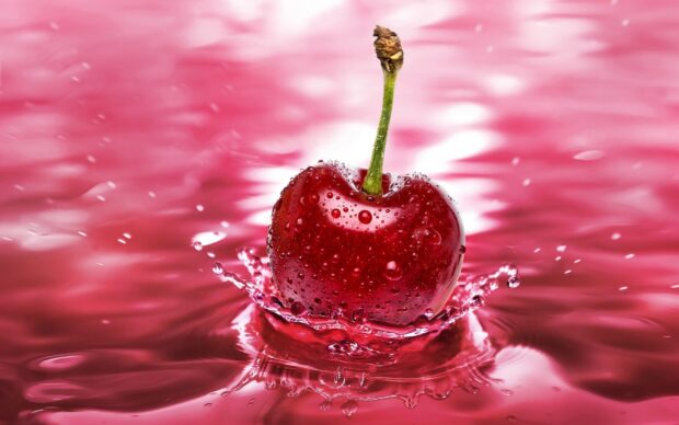 Fresh cherry with water droplets splashing on a red surface in vibrant HD quality