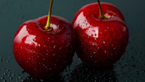 Fresh cherry close up with water droplets on dark surface